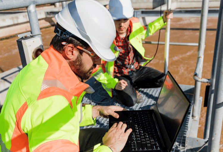 Two engineers inspecting a water treatment facility and monitoring water levels, highlighting the importance of precision and compliance in installing and managing Category 5 backflow prevention systems.